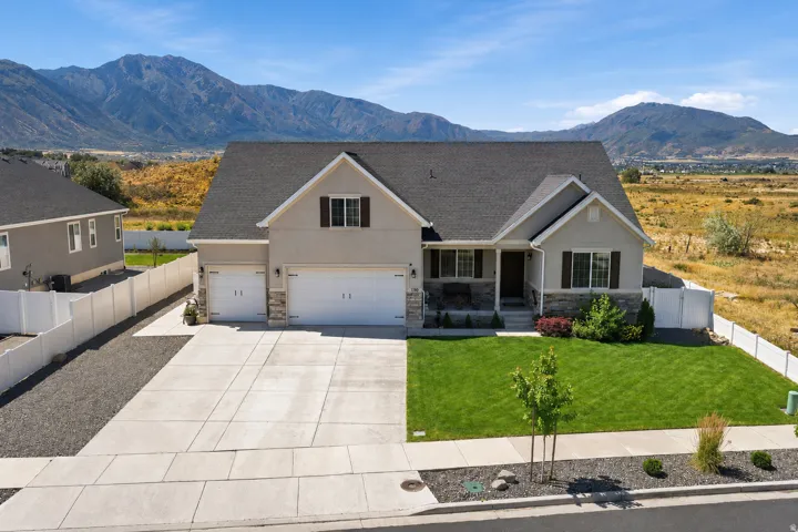 Contemporary residence featuring a light stucco exterior with stone accents, a dark shingle roof, and a 3-car garage