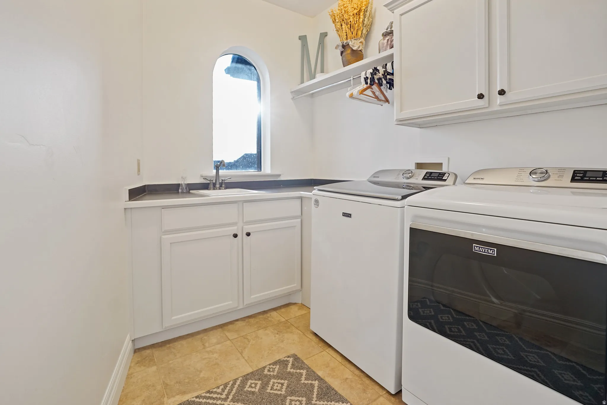 Laundry room with cabinet space, washer and dryer, and light tile patterned floors