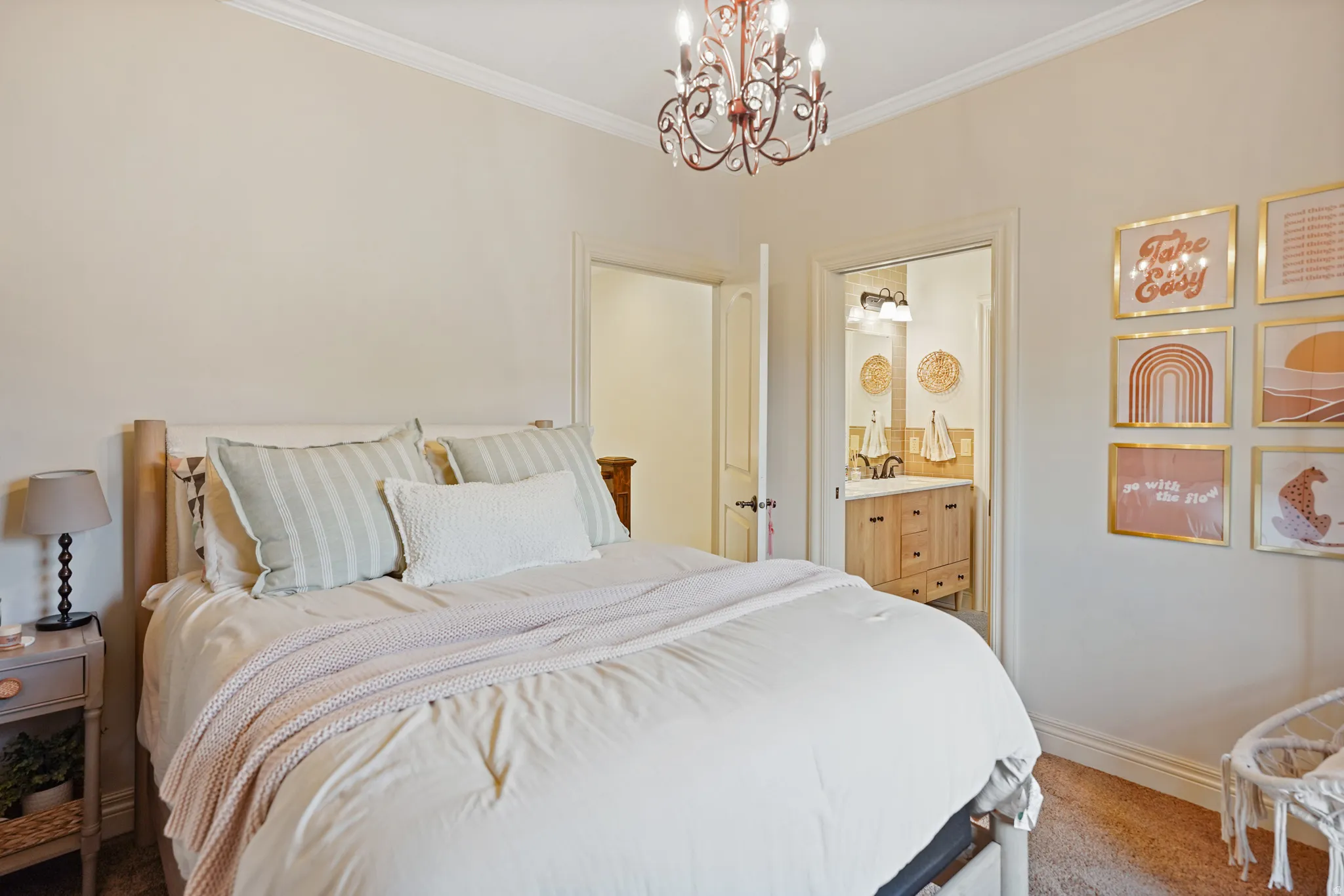 Bedroom featuring light colored carpet, a chandelier, crown molding, and ensuite bath