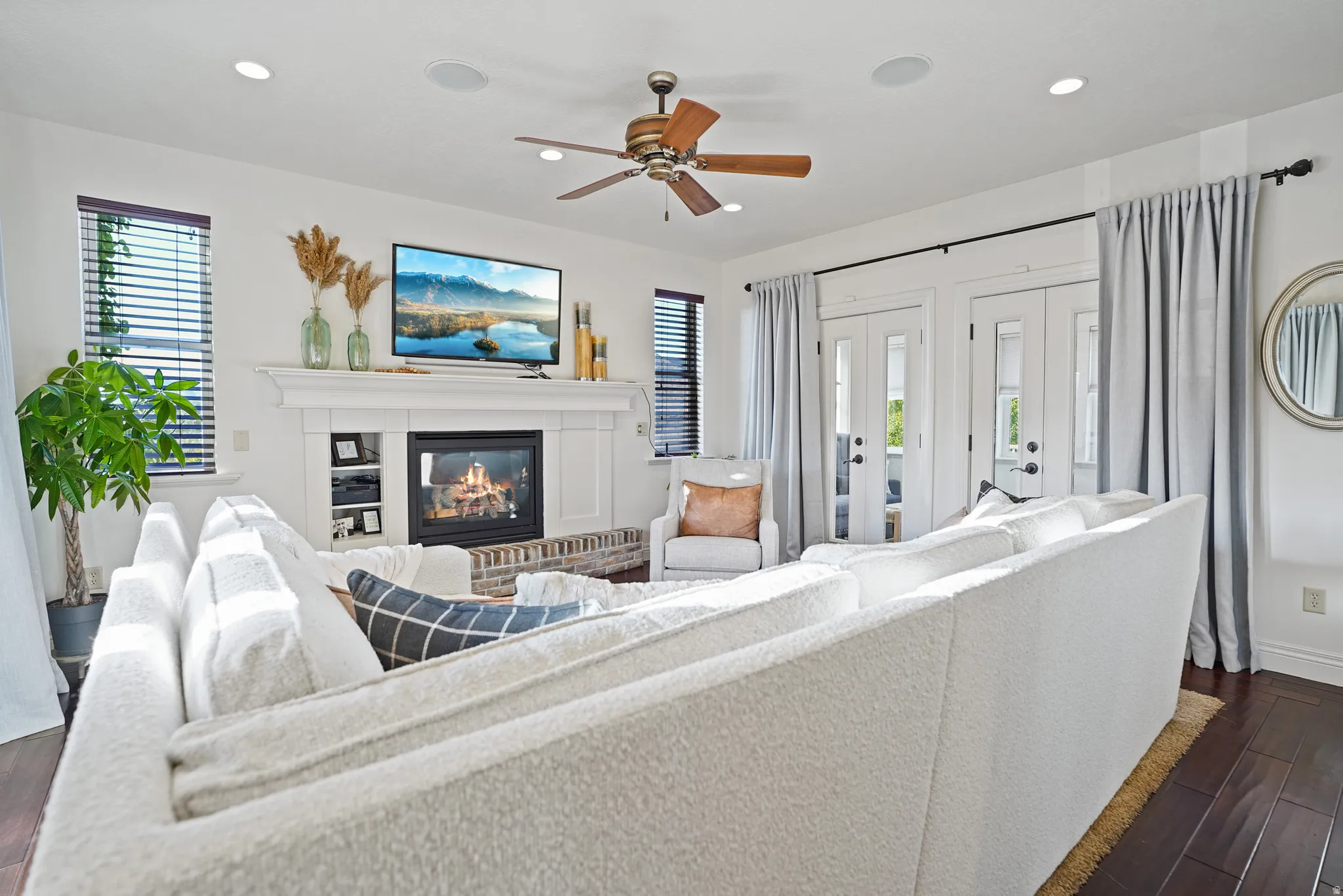 Living room featuring dark wood finished floors, a ceiling fan, a brick fireplace, and recessed lighting