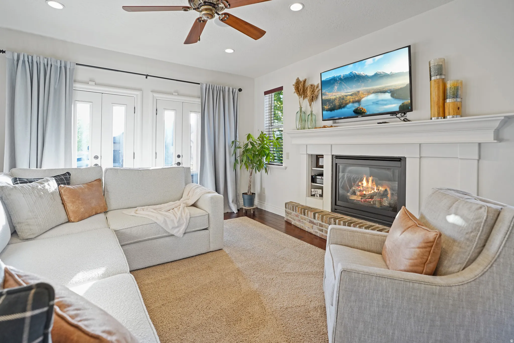 Living area with french doors, a fireplace, wood finished floors, recessed lighting, and a ceiling fan