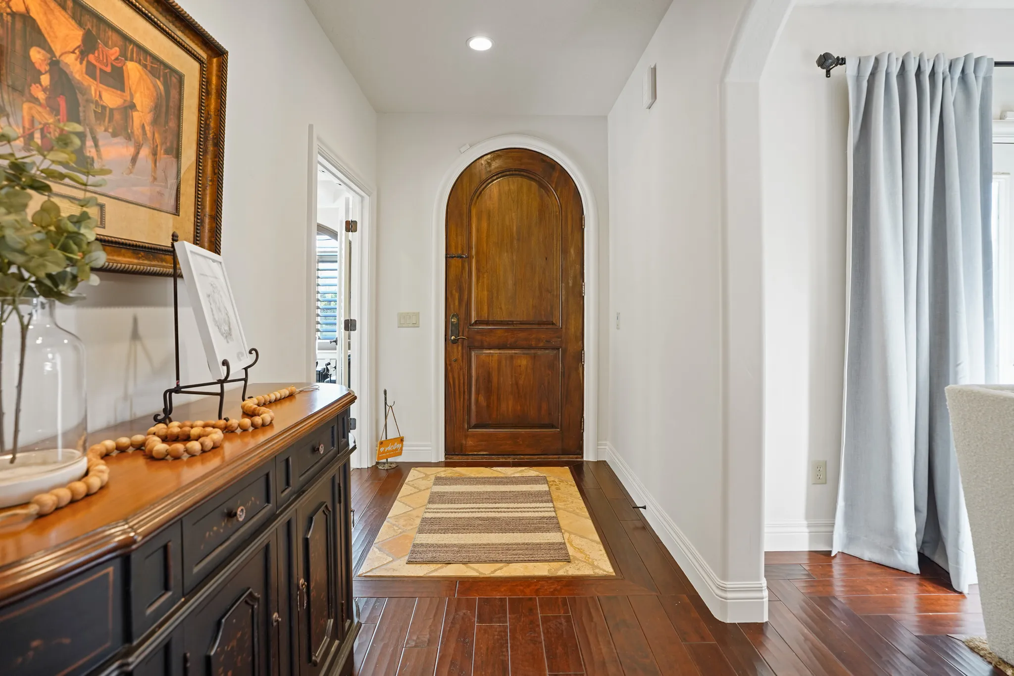Entrance foyer with arched walkways, dark wood-style floors, and recessed lighting