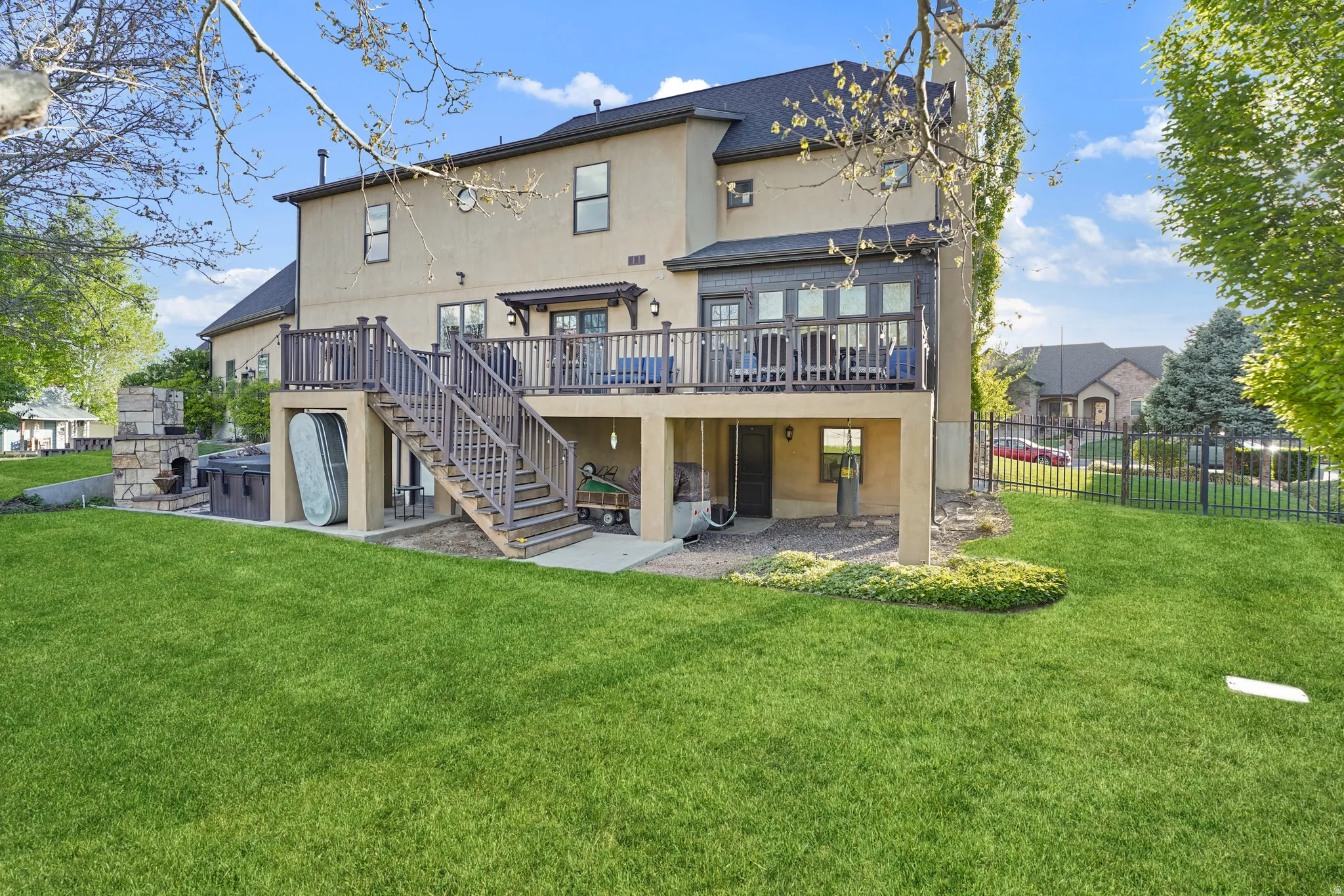 Rear view of house featuring a patio area, stucco siding, a wooden deck, and a hot tub