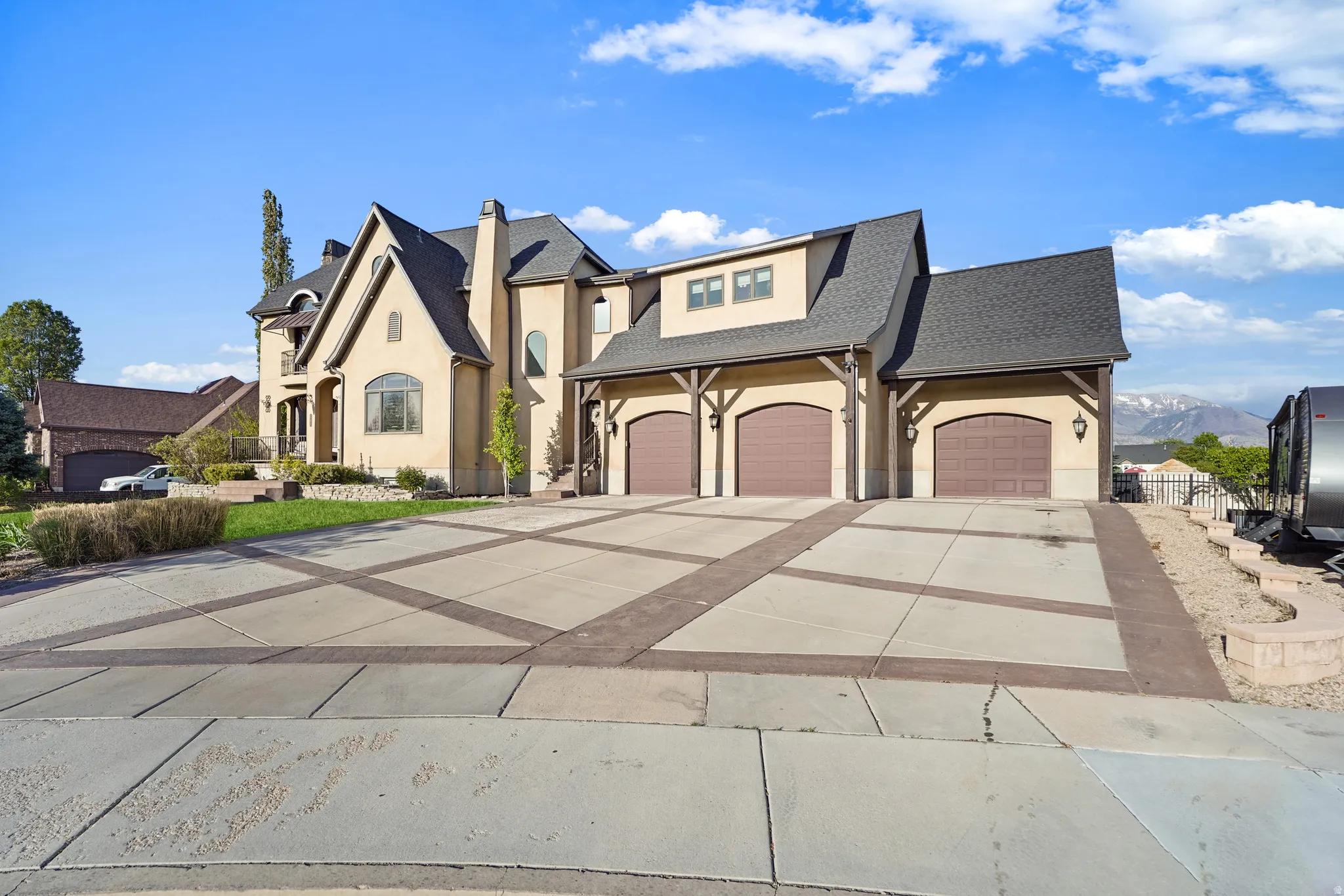 French provincial home featuring driveway, stucco siding, roof with shingles, and an attached garage