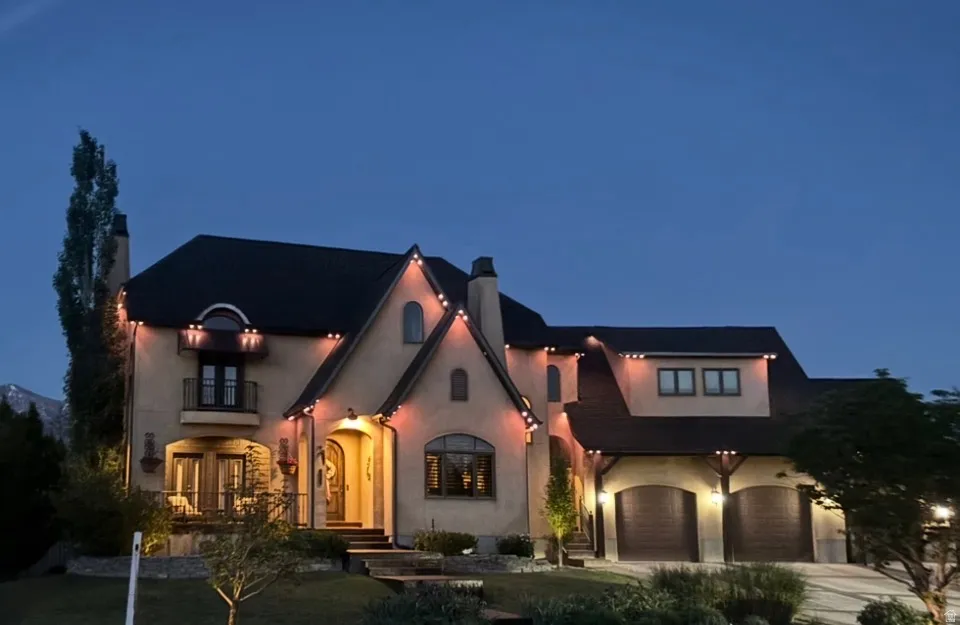 Stucco exterior residence with a dark-pitched roof, arched doorways, and a two-car garage featuring wood-finish doors