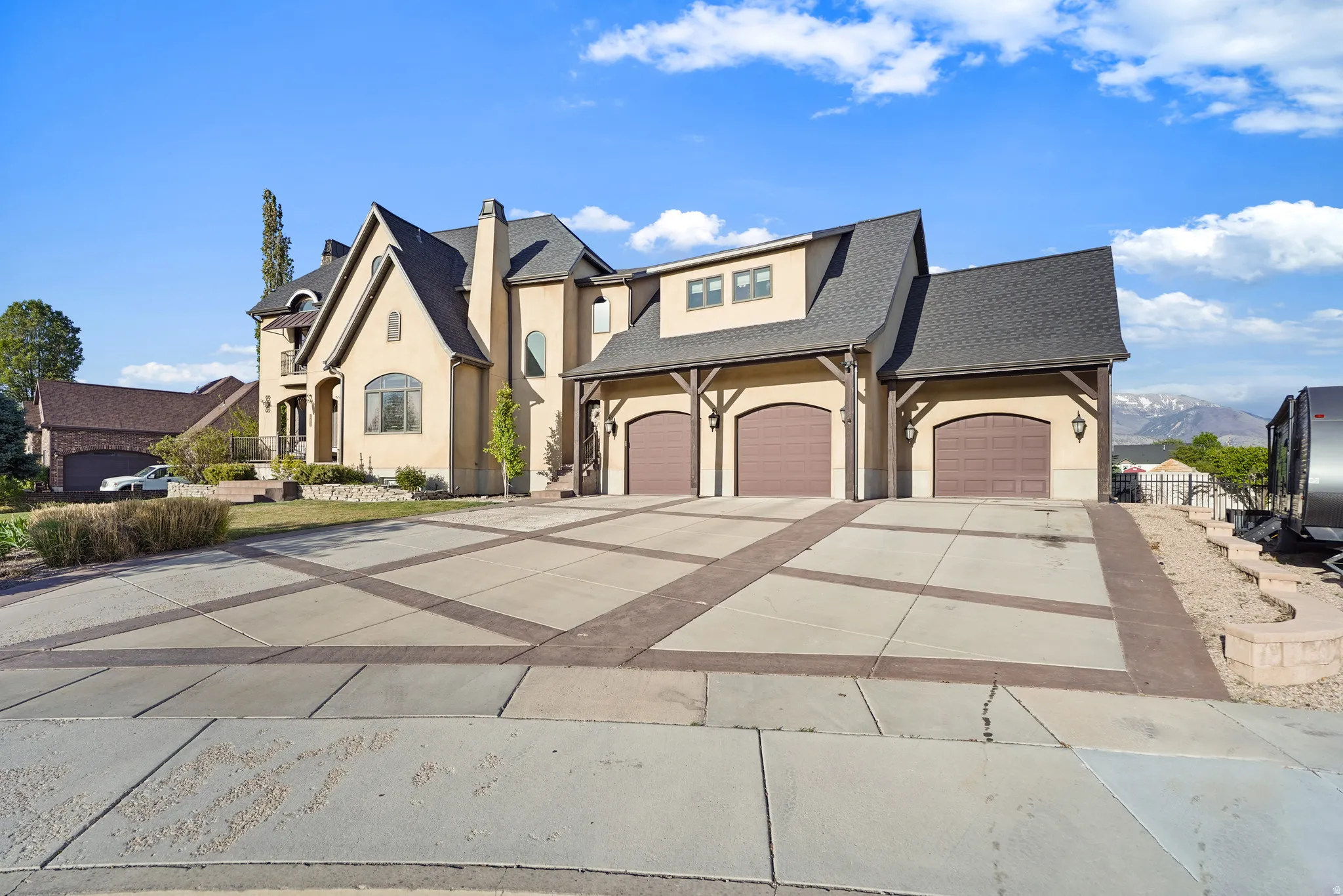 French country home featuring stucco siding, concrete driveway, a shingled roof, and an attached garage