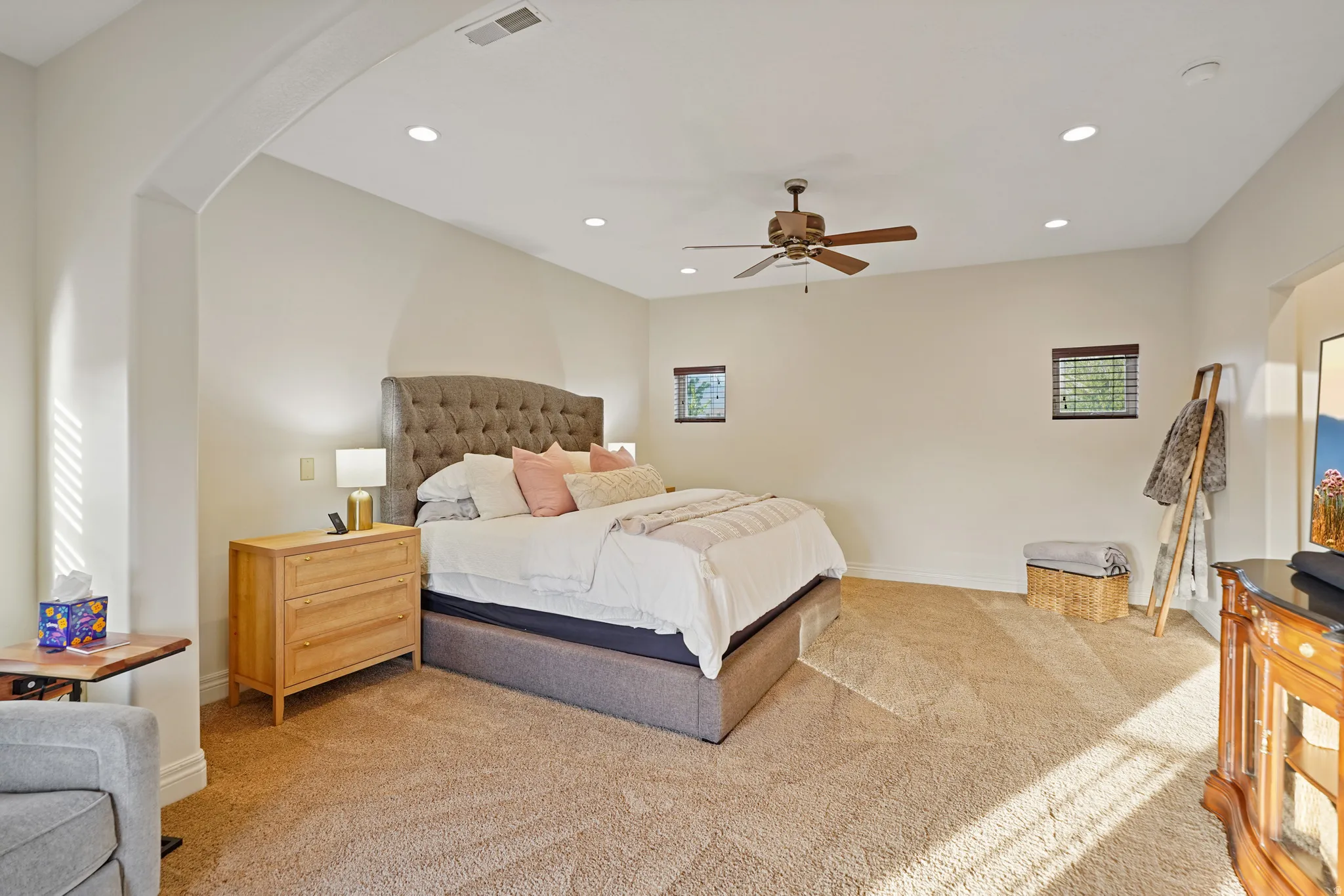 Primary bedroom featuring arched walkways, recessed lighting, light carpet, and ceiling fan