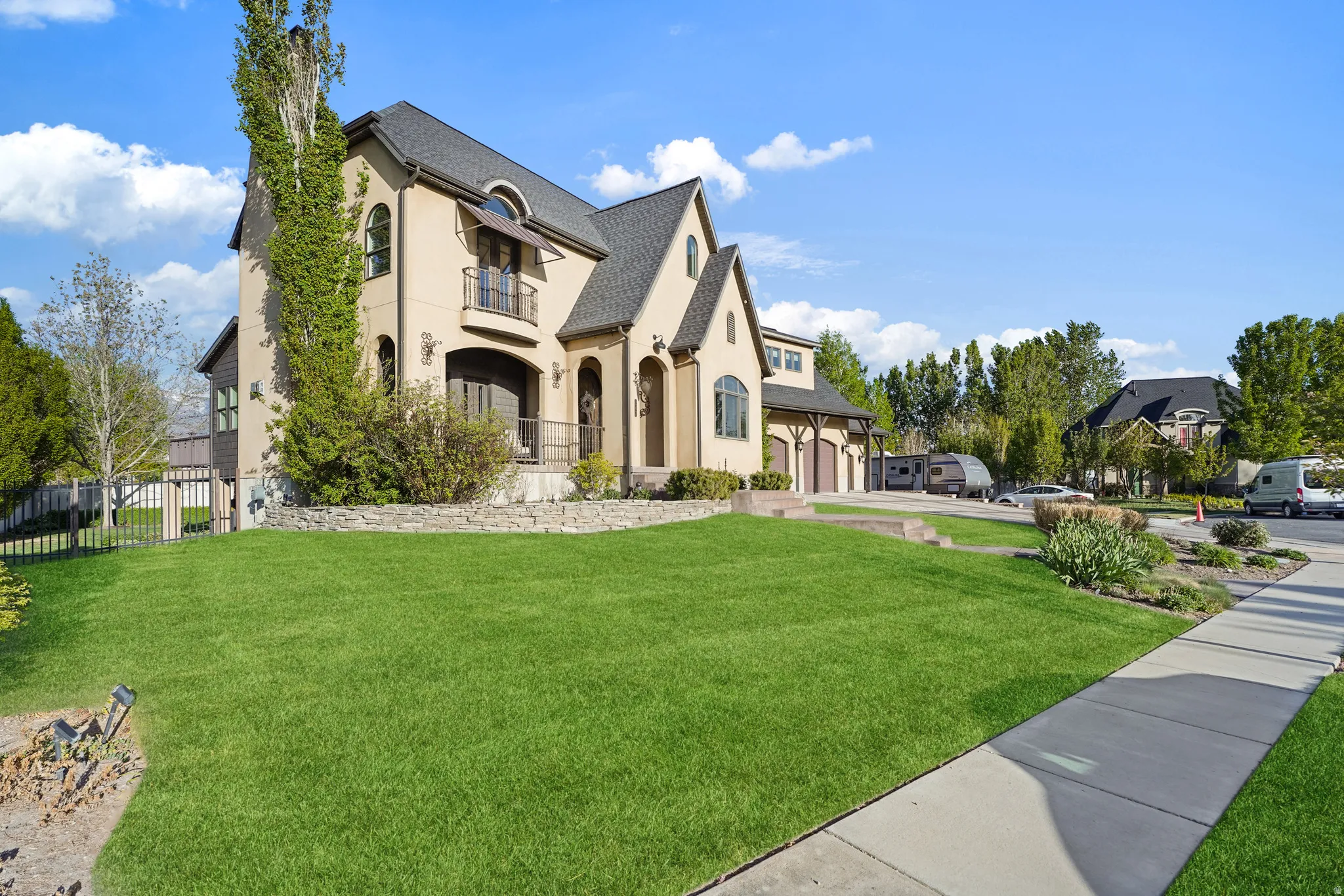 View of front of property featuring a front lawn, stucco siding, a garage, a balcony, and driveway