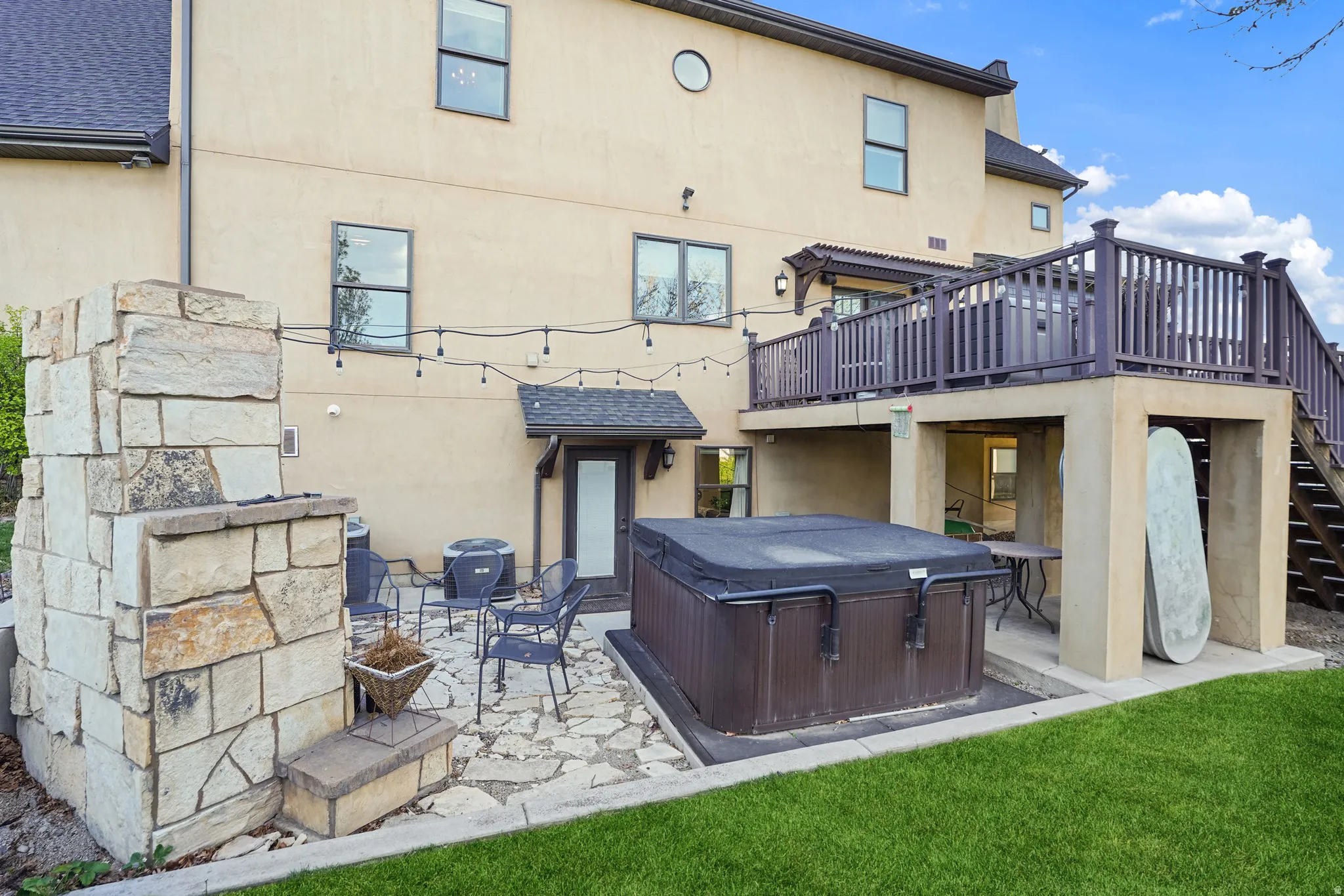 Back of house with a patio, a deck, a hot tub, and stucco siding
