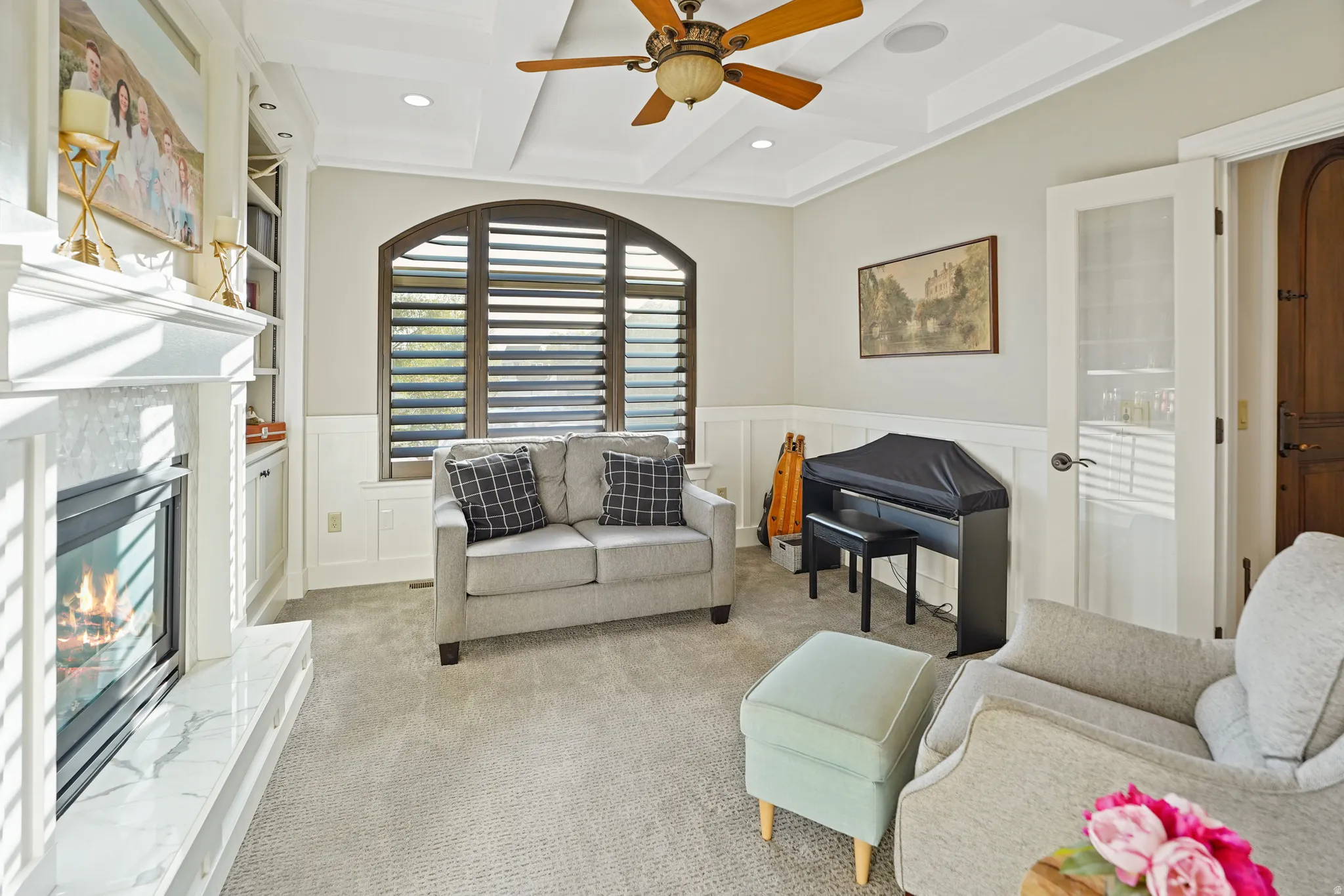 Formal living area featuring wainscoting, ceiling fan, a decorative wall, light carpet, and coffered ceiling