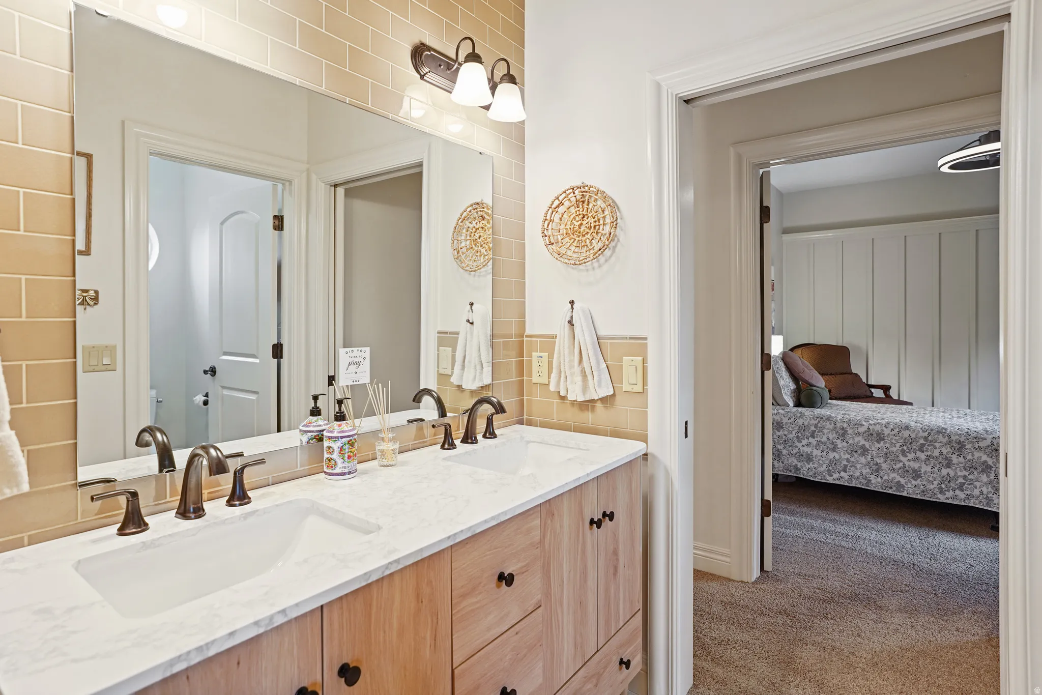Ensuite bathroom with double vanity and light colored carpet