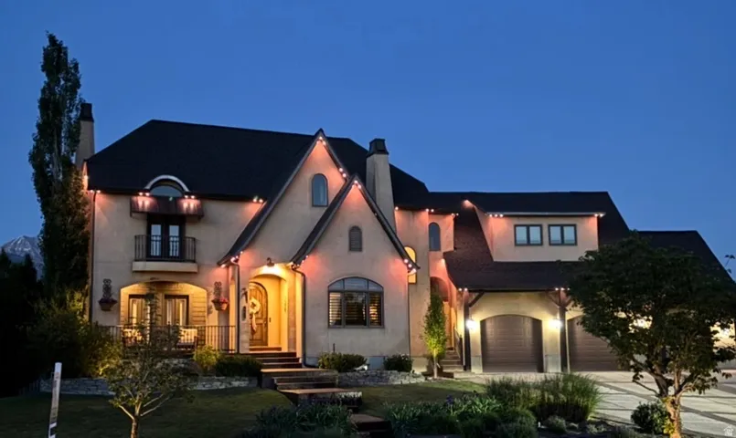 Stucco exterior featuring a prominent arched entry, a second-story balcony with wrought iron railing, and a three-car garage with arched doors