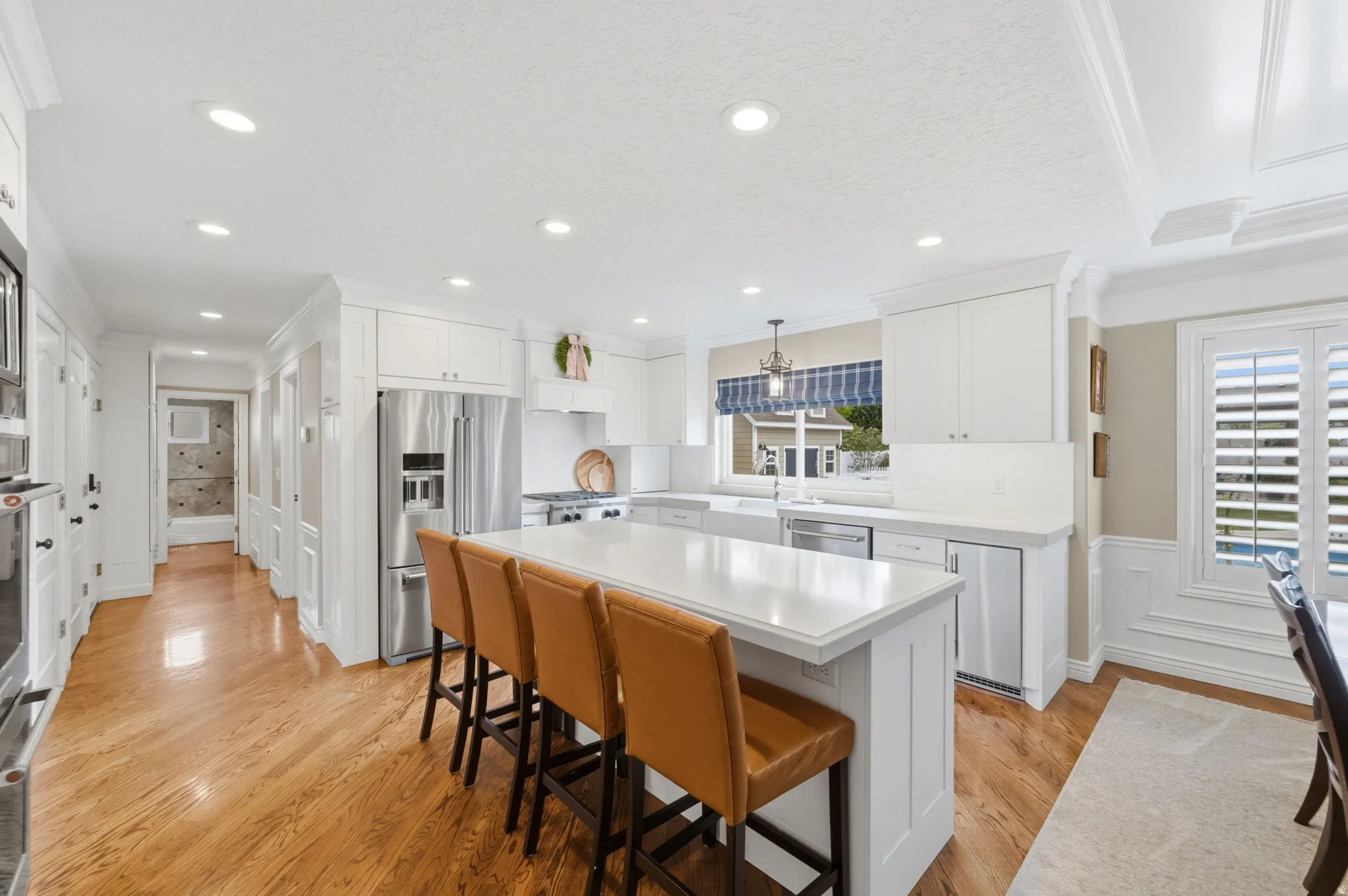 Fully remodeled custom Kitchen with crown molding, white cabinets, a breakfast bar area, stainless steel appliances, and hardwood floors