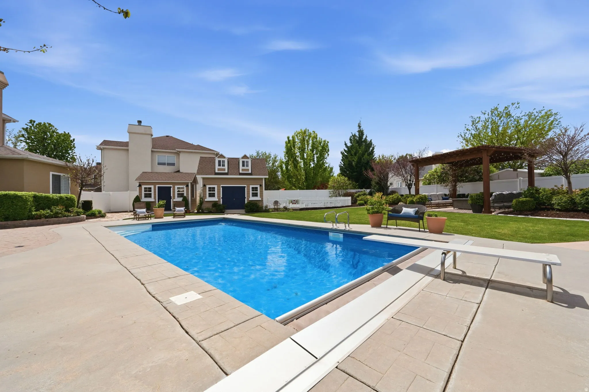 View of pool featuring patio surround, a fenced backyard, a pergola, and a diving board