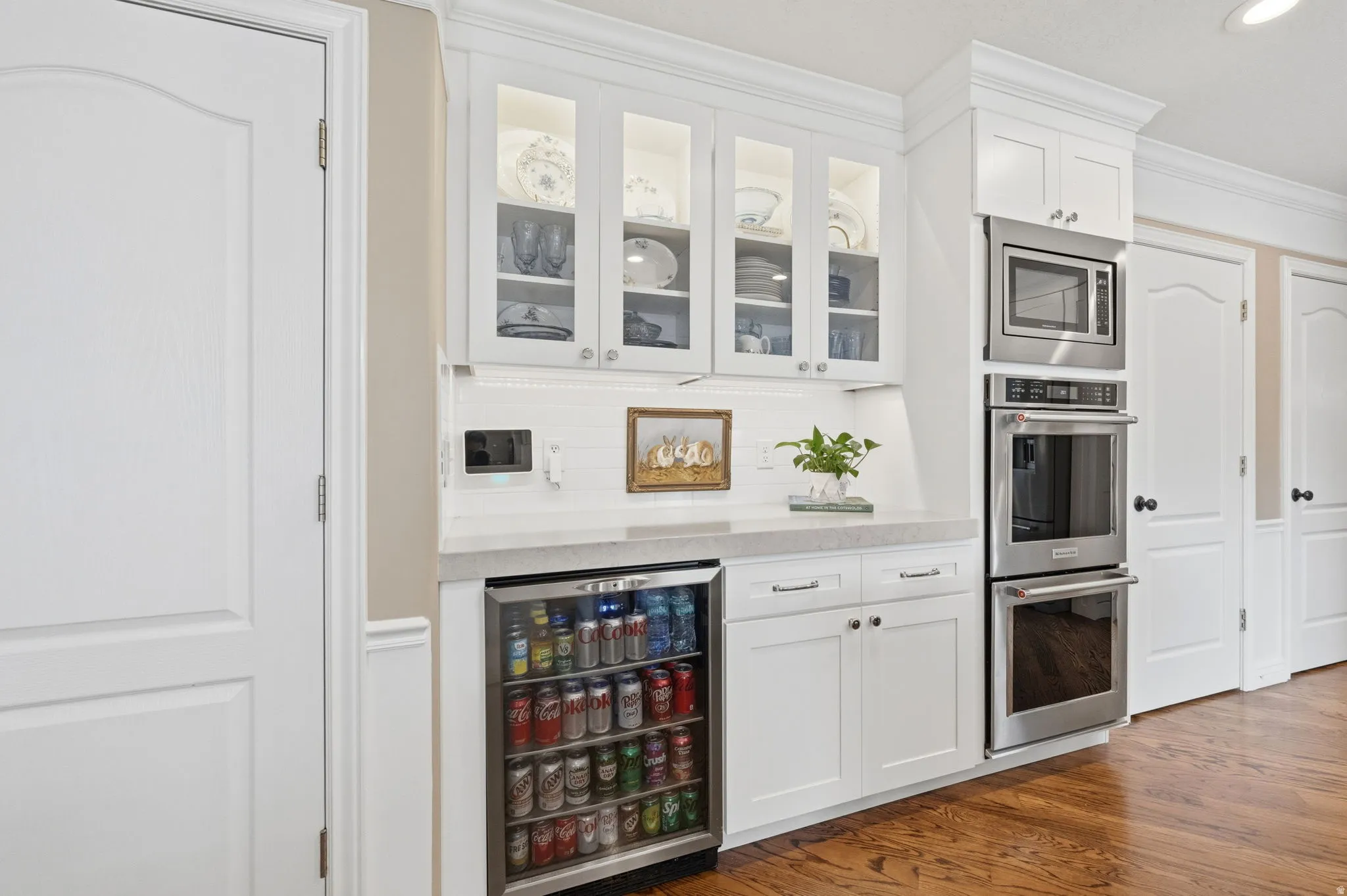 Dry ar area with white cabinetry, crown molding, glass fronted cabinets, stainless steel appliances, and mini refrigerator