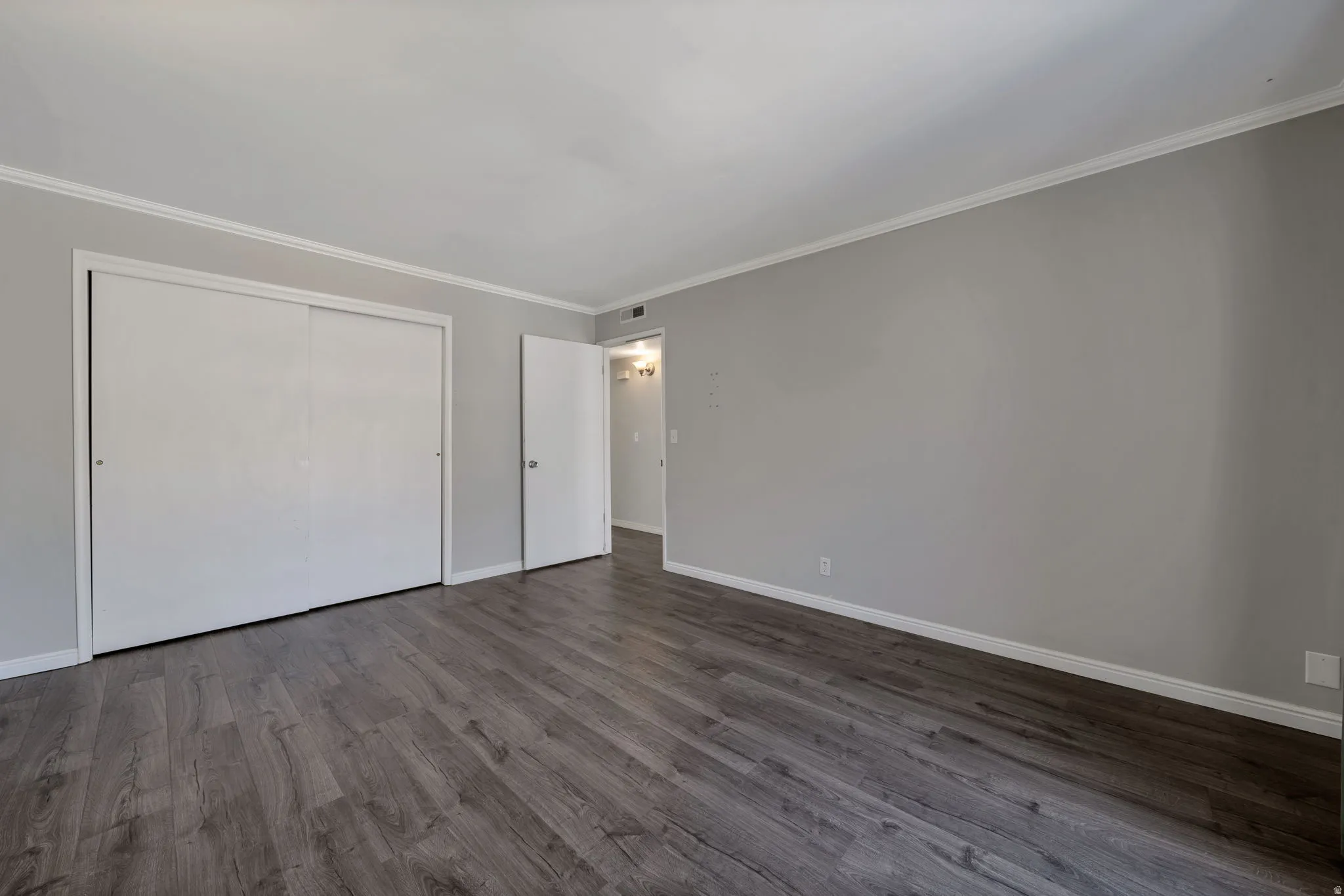 Unfurnished bedroom with ornamental molding, dark wood-type flooring, and a closet