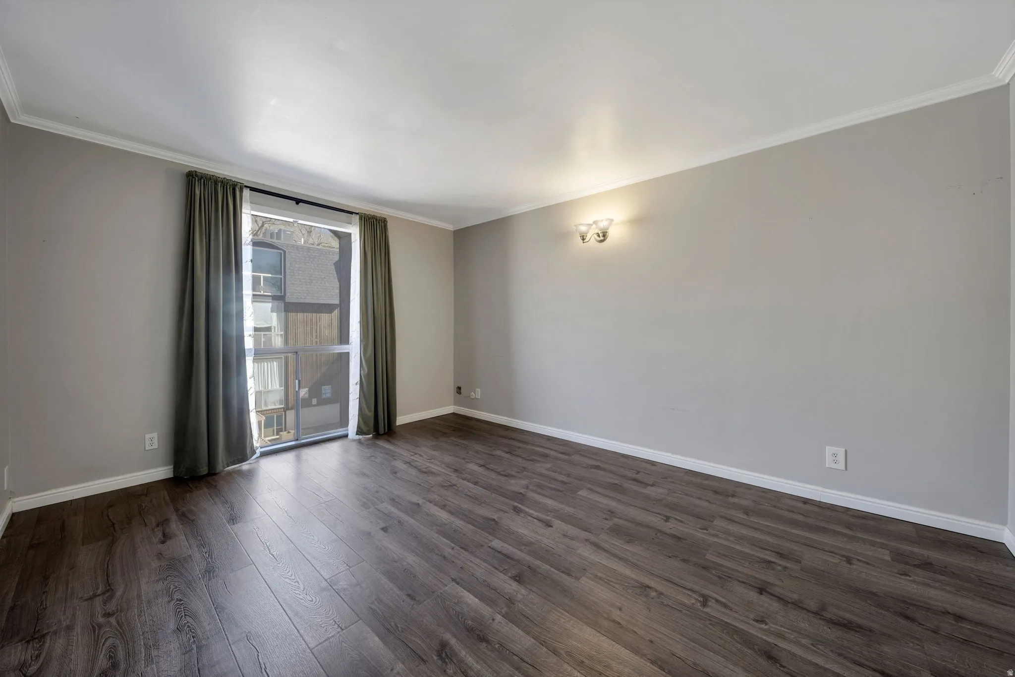 Empty room with crown molding and dark wood-type flooring