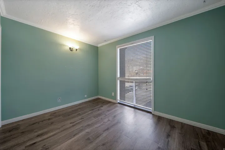 Spare room with dark wood-type flooring, a textured ceiling, and crown molding