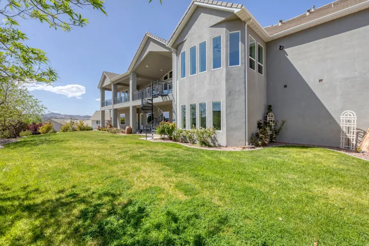 Rear view of house with a yard, stucco siding, a patio, and a mountain view