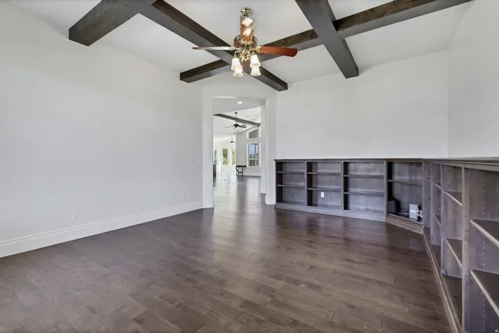 Unfurnished room featuring dark wood-style flooring, coffered ceiling, and ceiling fan