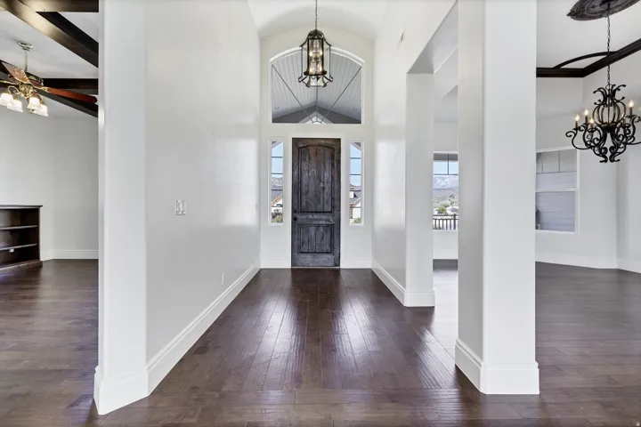 Foyer entrance with a chandelier, vaulted ceiling, dark wood finished floors, and ceiling fan