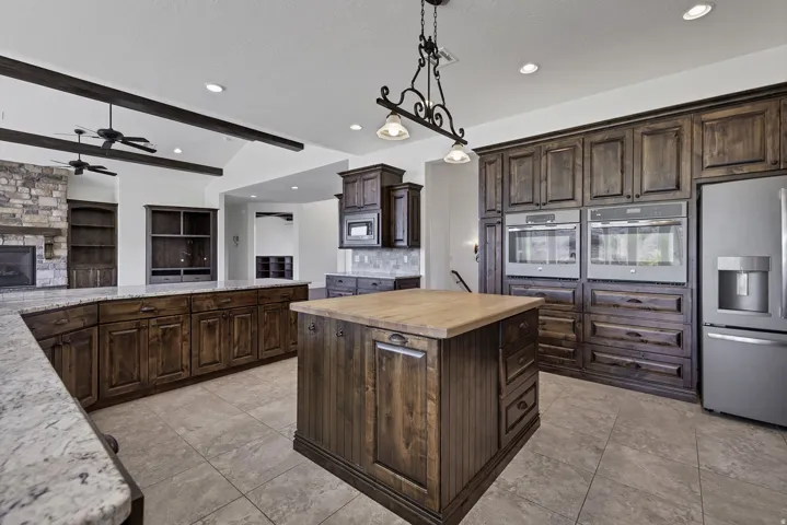 Kitchen with dark wood finish cabinets, stainless steel appliances, a center island, butcher block countertops, and a fireplace