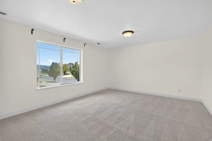 Expansive room featuring light-colored walls and grey carpet flooring
