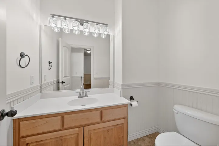 Bathroom vanity featuring a light wood-finish cabinet with white countertop and integrated sink
