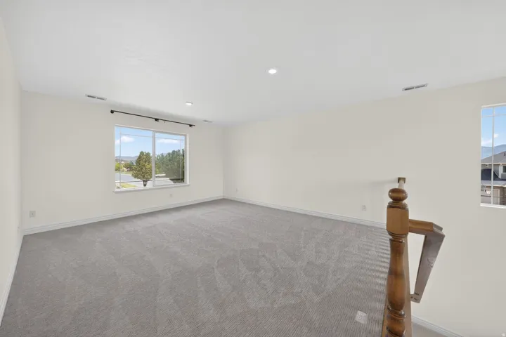 Spacious room featuring neutral carpeting, light-toned walls, and recessed lighting