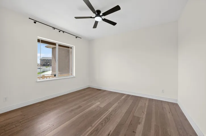 Interior space featuring wood-finish flooring, a contemporary ceiling fan, and a large window with white trim