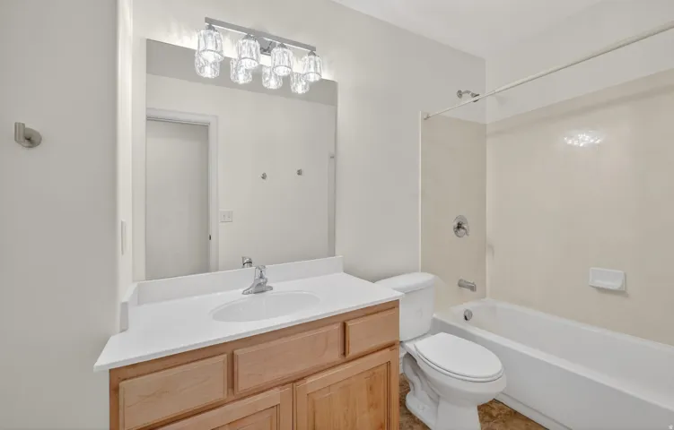 Bathroom featuring a wood-finish vanity with a white countertop, an undermount sink, and a modern light fixture