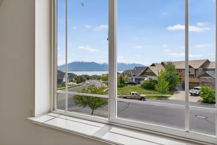 Large window with white trim, offering expansive scenery including a body of water and distant mountains