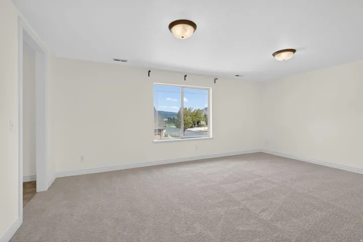 Carpeted room featuring a large window, neutral wall paint, and white trim