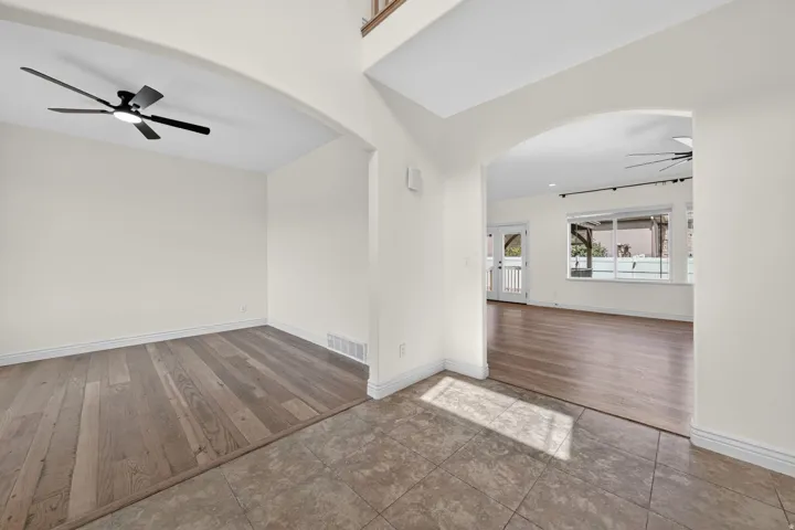 Spacious interior featuring a tiled entryway, arched doorways, wood-finish flooring, and ceiling fans