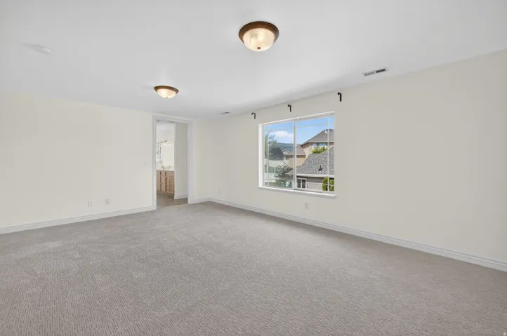 Spacious room featuring neutral carpeting, light-toned walls, and recessed ceiling lighting