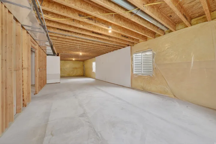 Unfinished basement presenting an open floorplan, exposed ceiling joists, and concrete flooring