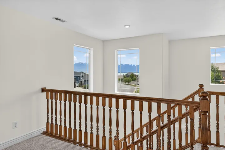 Upper-level landing featuring a wooden balustrade and carpeted flooring