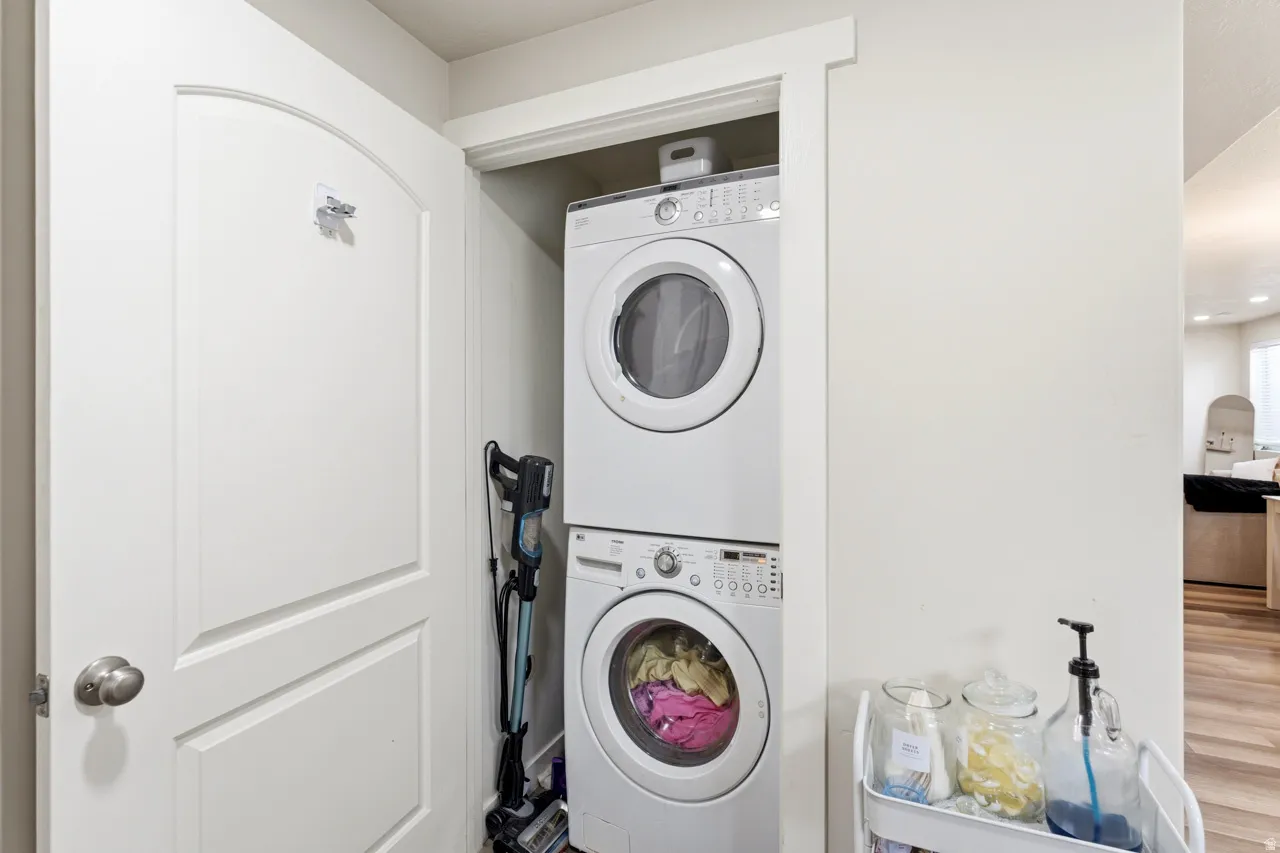 Laundry area featuring stacked washer / drying machine and wood finished floors