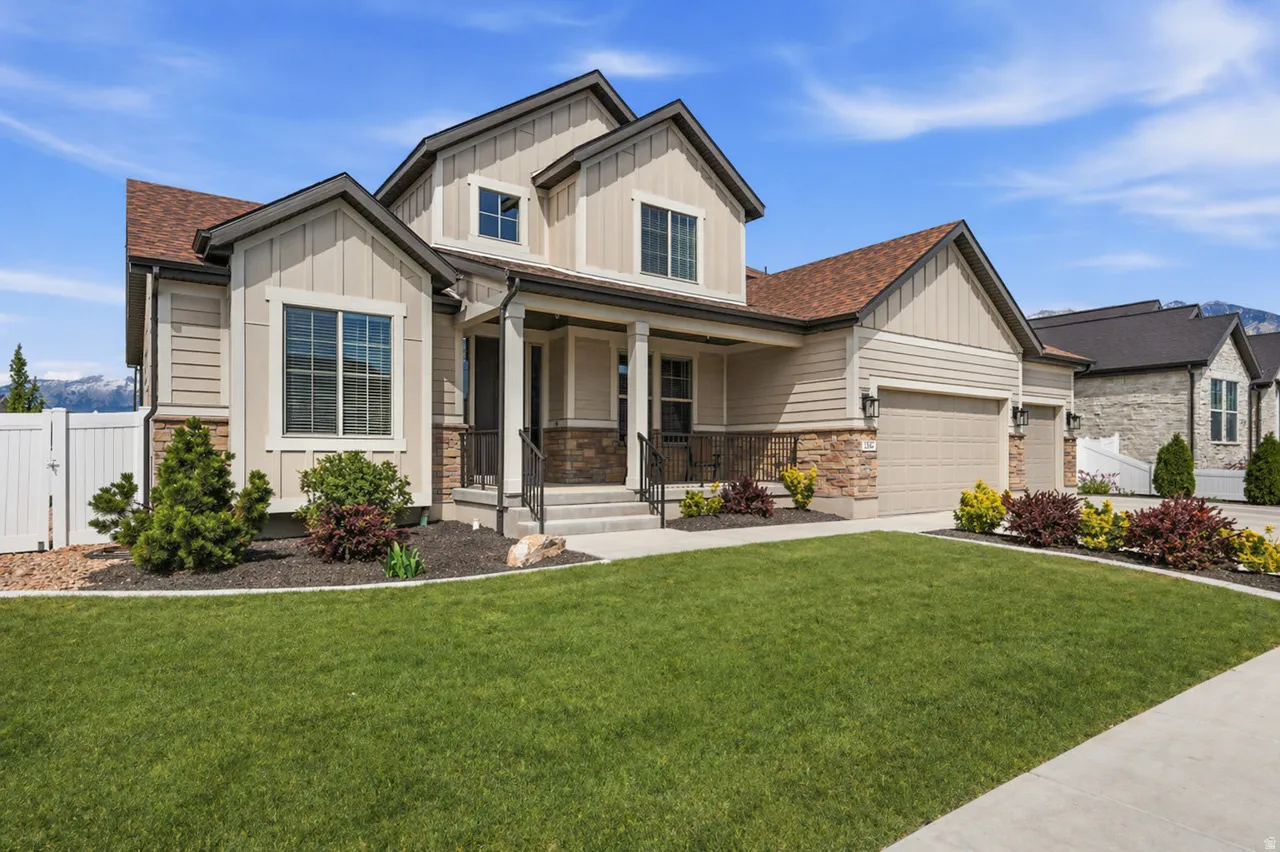 AI enhanced lawn.  Craftsman-style home with board and batten siding, a porch, stone siding, an attached garage, and a shingled roof