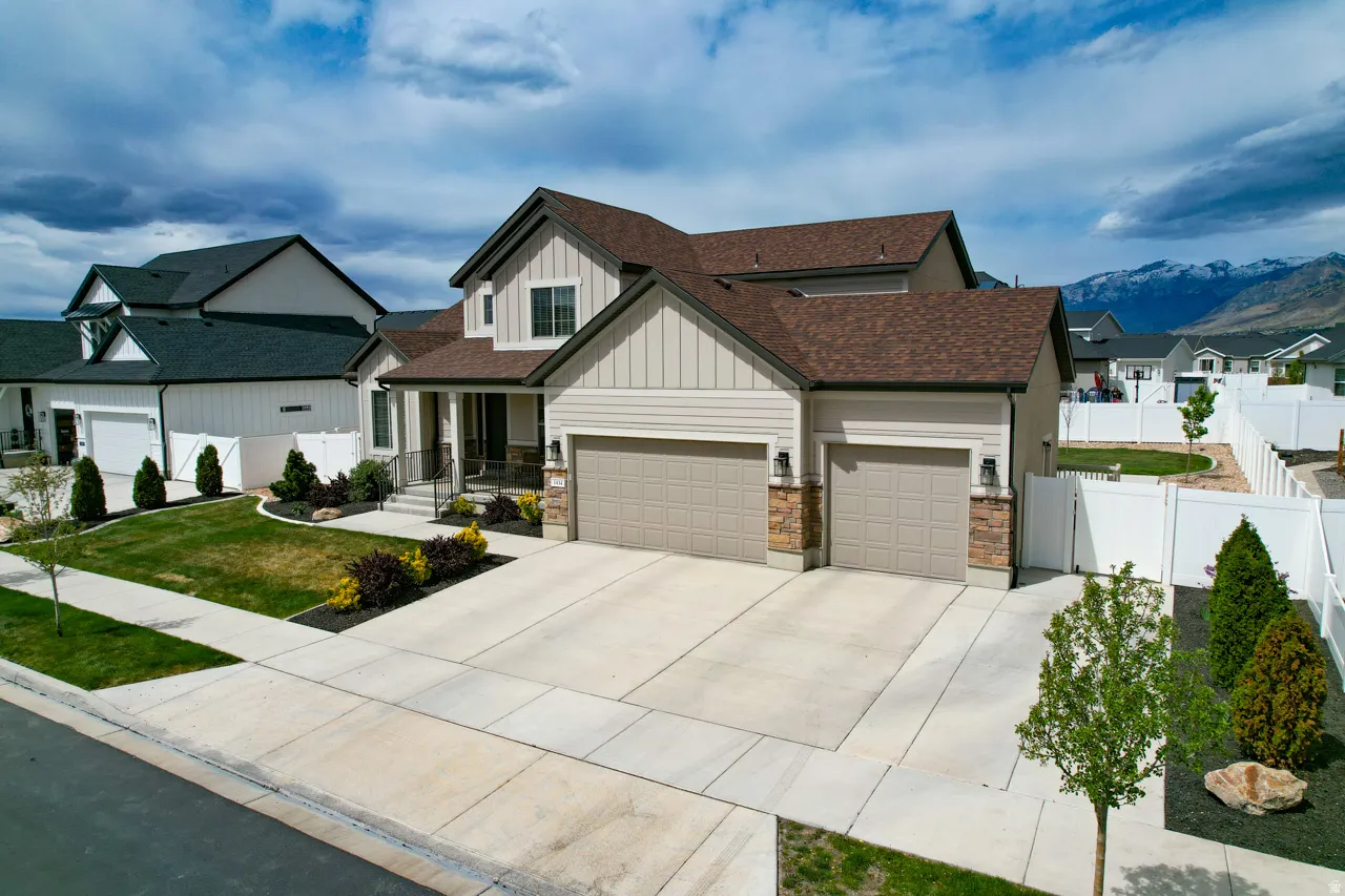 View of front of home with board and batten siding, an attached garage, covered porch, a residential view, and driveway