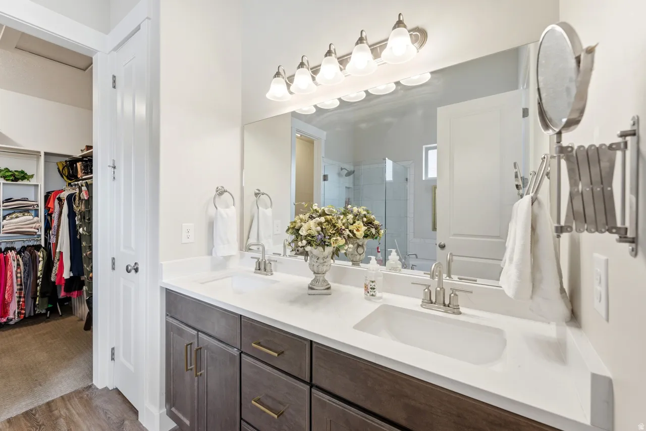 Full bathroom with double vanity, a shower stall, and a spacious closet