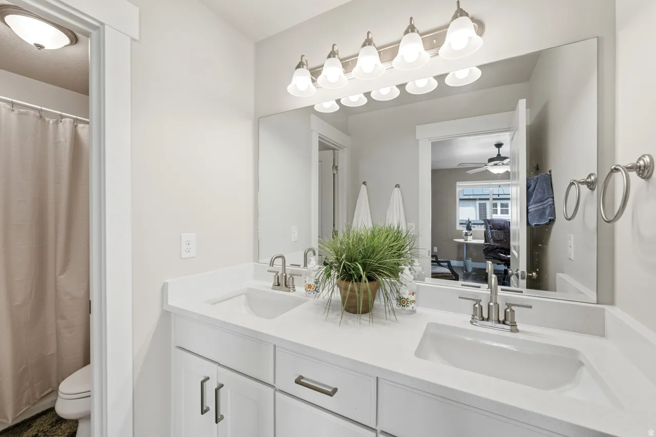 Bathroom featuring double vanity, a shower with curtain, and ceiling fan