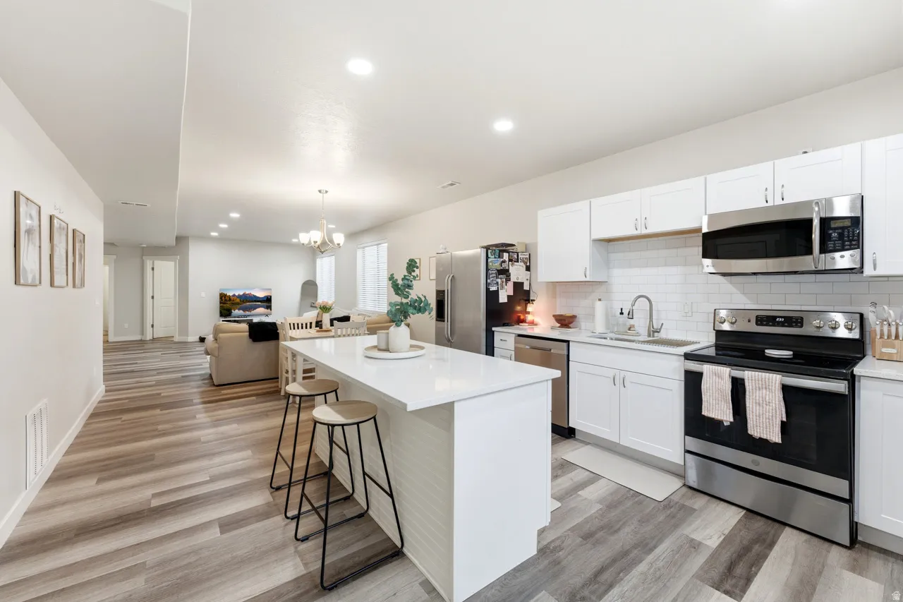 Kitchen featuring stainless steel appliances, open floor plan, a breakfast bar area, white cabinets, and a kitchen island