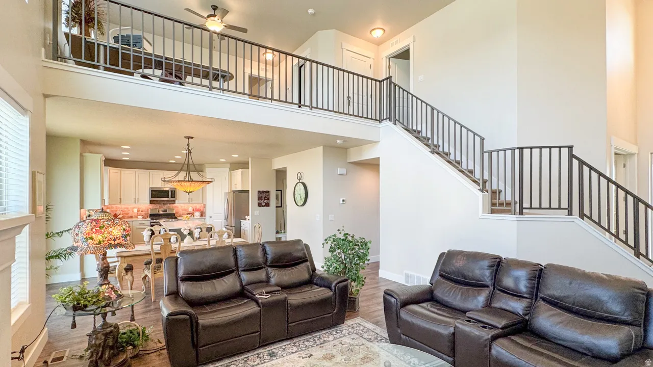 Living area with a ceiling fan, a high ceiling, wood finished floors, and recessed lighting