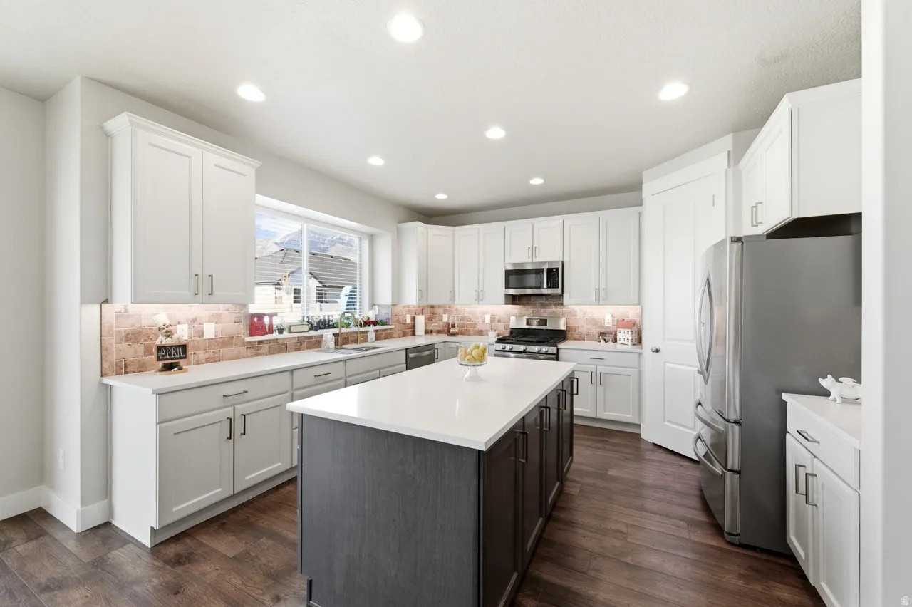 Kitchen featuring stainless steel appliances, a center island, dark wood-style floors, dual tone cabinetry, and recessed lighting