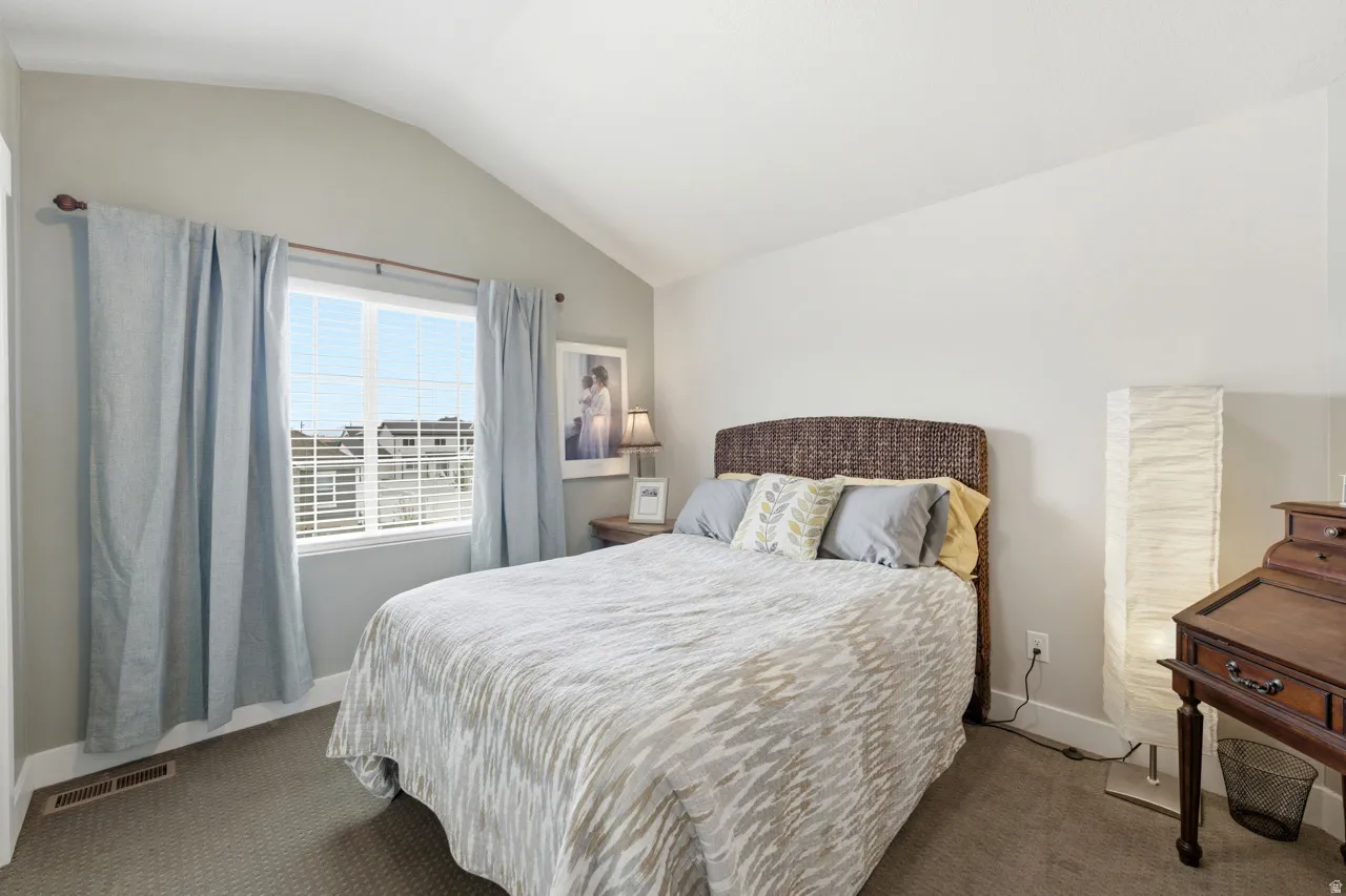 Carpeted bedroom with vaulted ceiling and baseboards