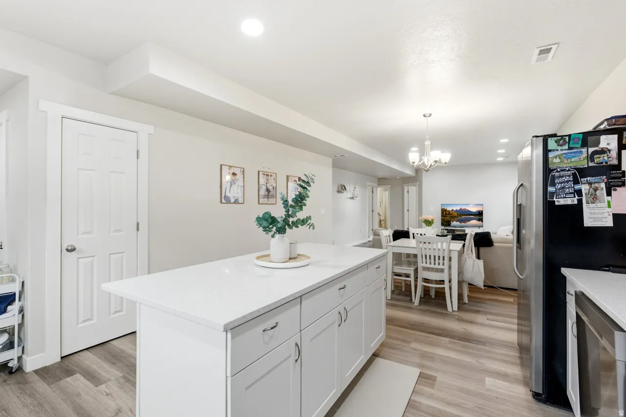 Kitchen with stainless steel fridge, a center island, open floor plan, and light wood-type flooring