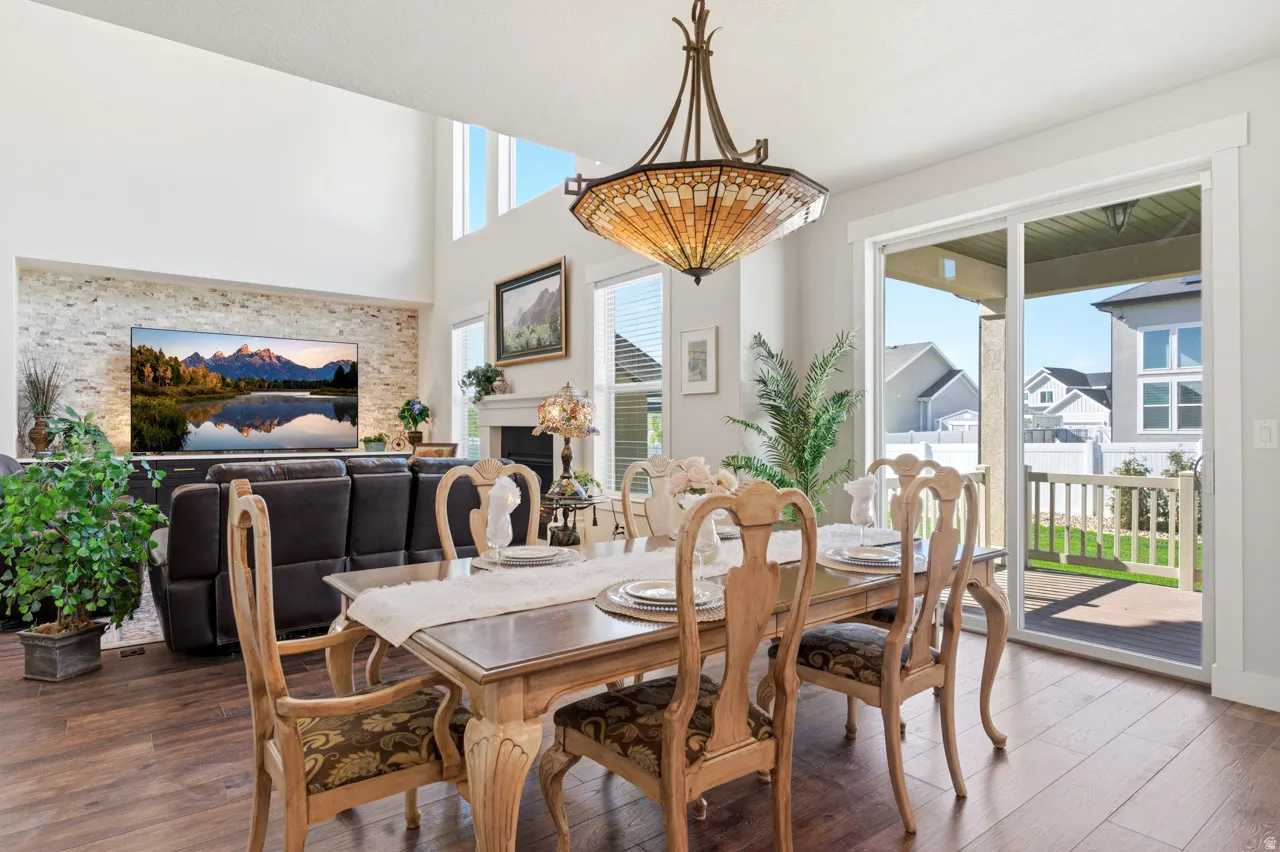 Dining room featuring wood finished floors, a fireplace, and a high ceiling