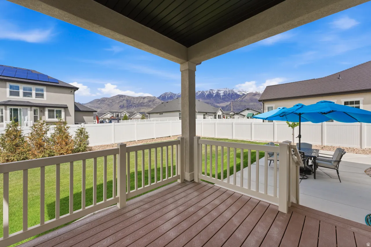 Deck with outdoor dining space, a fenced backyard, a mountain view, and a residential view
