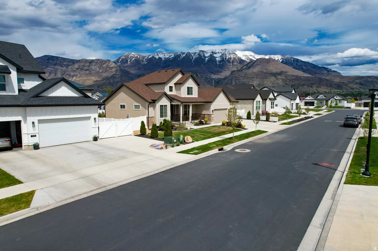 View of asphalt road with a gate, a residential view, a mountain view, and sidewalks